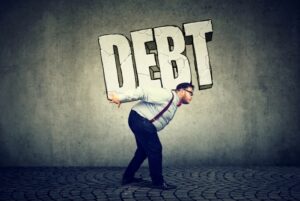 Man carrying large “DEBT” letters on his back, symbolizing the burden of taking on debt and financial decision-making