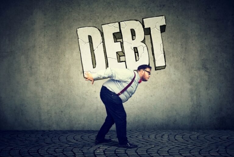 Man carrying large “DEBT” letters on his back, symbolizing the burden of taking on debt and financial decision-making