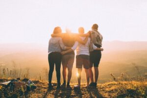 Four friends embracing at sunset symbolizing wealth, happiness, and meaningful connection.