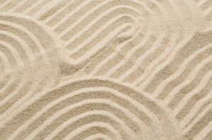 A calming texture of raked sand in a Zen garden, symbolizing structure, intentionality, and control for a wealth management article.
