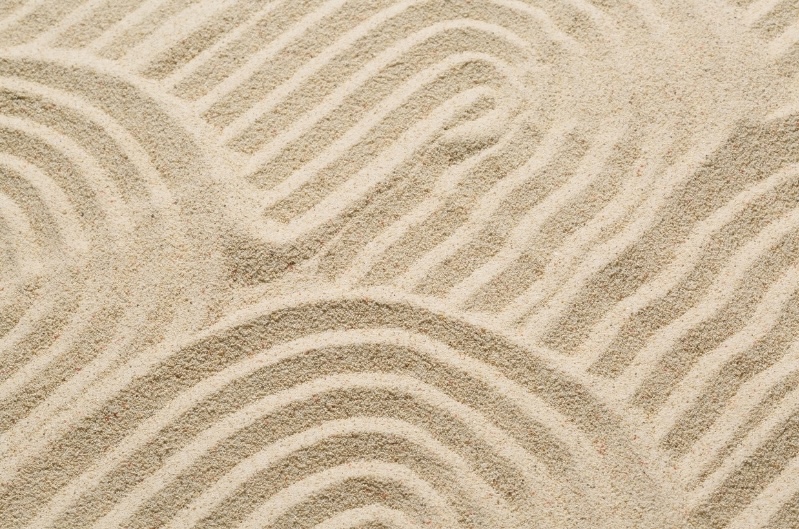 A calming texture of raked sand in a Zen garden, symbolizing structure, intentionality, and control for a wealth management article.