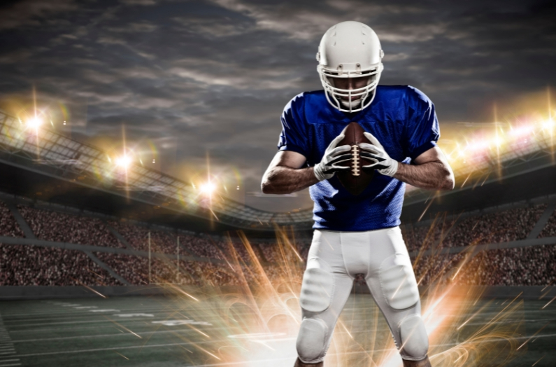 A young football player holding a ball on a floodlit field, illustrating an article on NIL financial planning for athletes and their families.